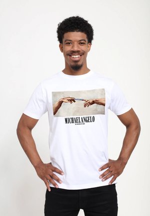 Bílá bavlněná tričko s potiskem dvou rukou sahajících k sobě, s textem "MICHAELANGELO" a "STVOŘENÍ ADAMA".