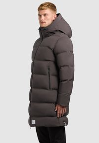 Mørkegrå polstret parka med høj krave, lynlåslommer og aftagelig hætte, der har en glat overflade og moderne design.