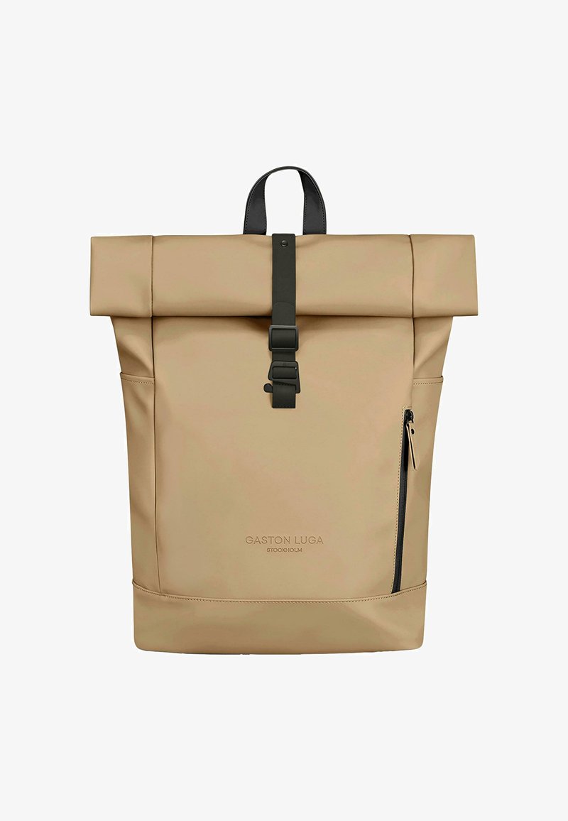 Beige rulle-top rygsæk lavet af vandtæt materiale med sort spænde rem, sidelomme med lynlås og prægede logo foran.