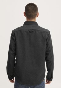 Graue, strukturierte Hemdjacke mit Kragen, langen �Ärmeln und Knopfmanschetten. Die Rückansicht zeigt Nahtlinien und eine Schlaufe am Hals.