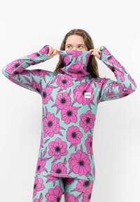 T-shirt à manches longues en vert menthe avec de grands motifs floraux roses. Doté d'un col haut et pliable et d'une coupe ajustée. Étiquette de la marque visible sur la poitrine.