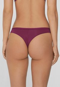 Bordeaux bikini onderstuk met een zachte textuur, laag uitgesneden ontwerp en minimale bedekking, met een rekbare tailleband en naadloze randen.
