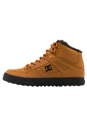 Ruskean nahkakorkki-nilkkurit mustalla kumipohjalla, harmaalla fleece-vuorauksella, oransseilla yksityiskohdilla ja rei'itetyllä yksityiskohdalla. DC-logo näkyvissä.