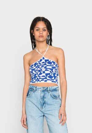 Top cropped halter azul e branco com padrão, alças finas e um design abstrato único, combinado com jeans de denim claro de cintura alta.