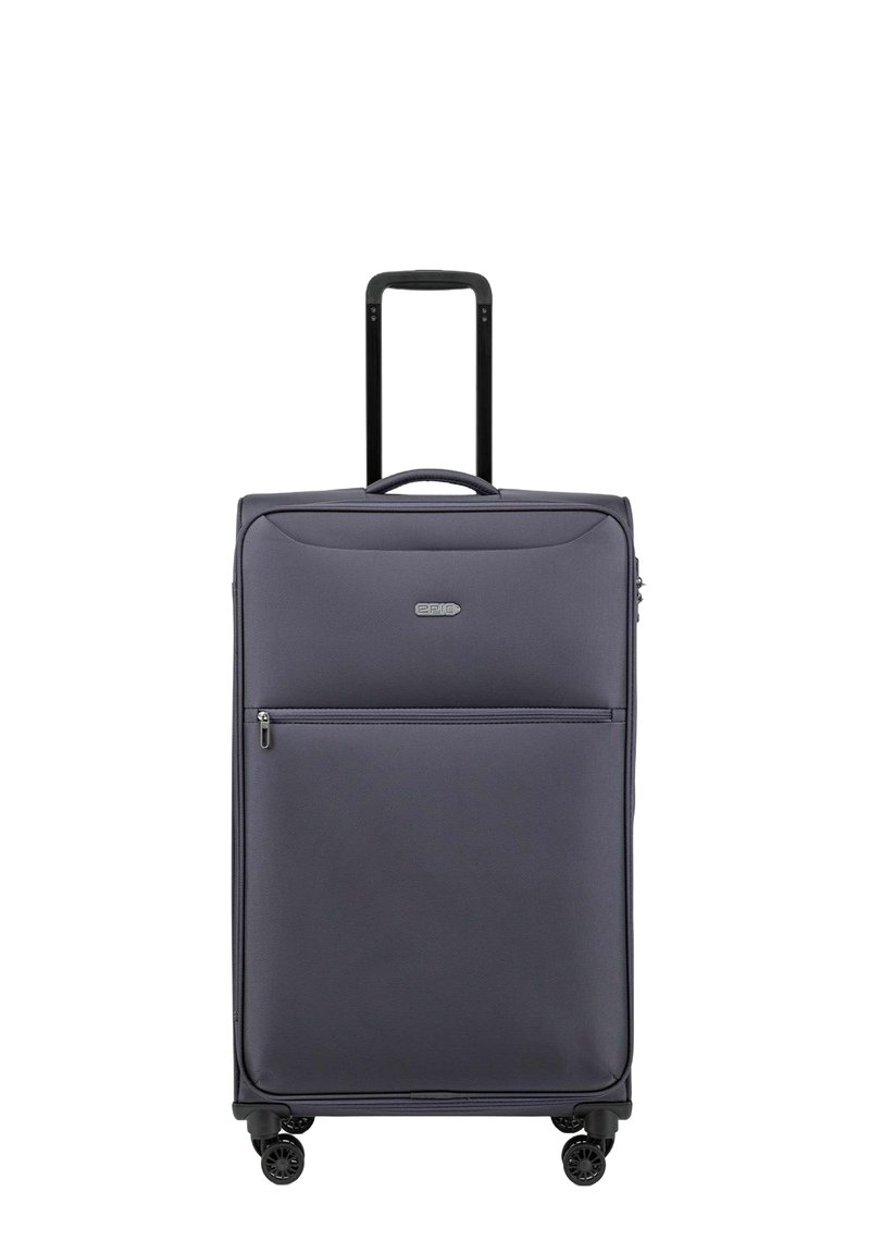 Maleta blanda gris con un bolsillo frontal con cremallera, mango retráctil negro, cuatro ruedas y una textura suave. Apta para viajar.