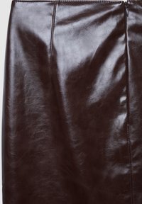 Jupe crayon en cuir marron avec une finition brillante, présentant une texture lisse, un design épuré et une fermeture à glissière sur le côté.