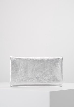 Pochette rectangulaire argentée brillante avec une texture métallique lisse, placée sur un socle carré blanc sur fond gris clair uni.