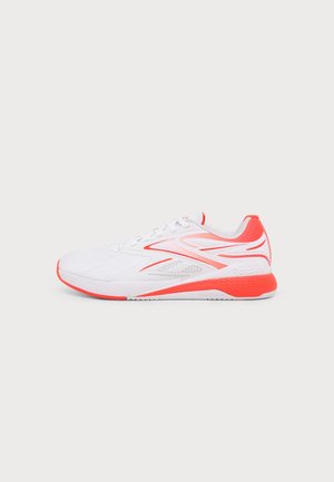 Biało-koralowy sportowy sneaker z wiązaniem na sznurowadła, oddychającą siateczką i teksturowaną podeszwą, widoczny z boku na jednolitym tle.