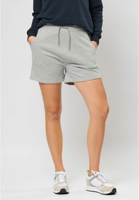 Grå shorts i bomullsblandning med elastisk midja och dragsko, med sidofickor och en avslappnad passform. Bärs med vita träningsskor.
