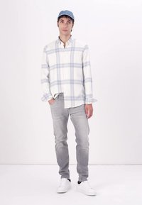 Rutet skjorte i hvit og lys blå, knapp-og-design; lys grå jeans; hvite sneakers; blå caps; flate teksturer; avslappet stil.