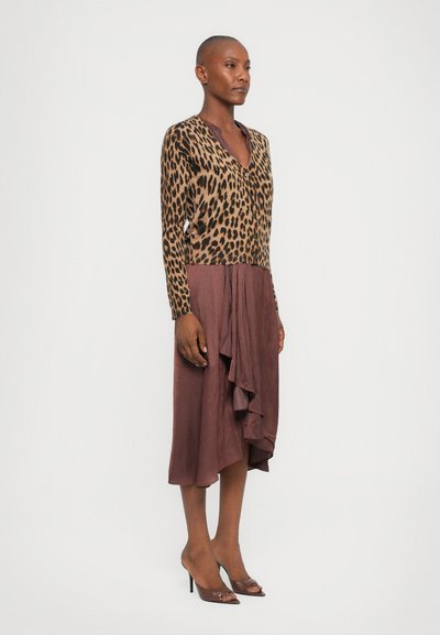 Leopard print cardigan with long sleeves, paired with a burgundy wrap skirt featuring a ruffled hem. Transparent heeled sandals complete the look.