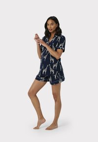 Conjunto de pijama corto azul marino con estampado de jirafas, que incluye una camisa con cuello y pantalones cortos a juego, fabricado en una tela suave.