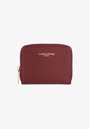 Portefeuille en cuir bordeaux avec une finition texturée, logo doré sur le devant et fermeture zippée. Forme rectangulaire compacte.
