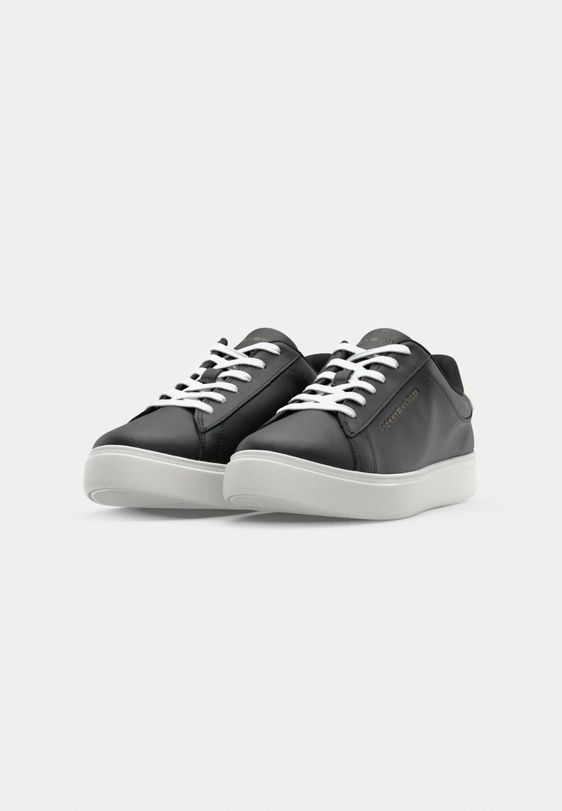 Zapatillas de cuero negras con cordones blancos, punta redondeada y diseño minimalista. Presentan una suela blanca acolchada y un sutil detalle de marca.