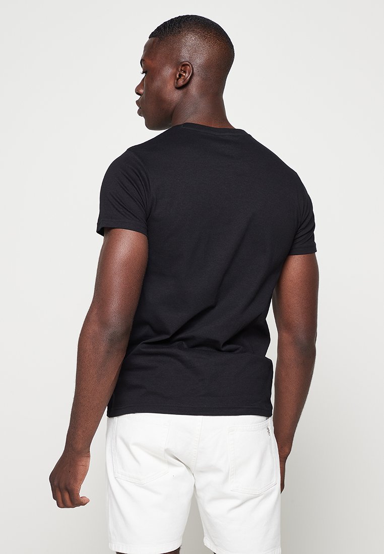 Czarna bawełniana koszulka z krótkim rękawem i okrągłym dekoltem, wyeksponowana z tyłu. Gładka tekstura, dopasowany krój.