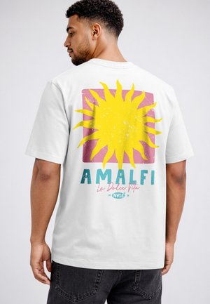 Mann trägt weißes T-Shirt mit großem gelbem Sonnengrafik, rosa Quadrat und Schriftzug "AMALFI La Dolce Vita" auf dem Rücken.