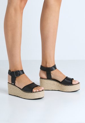 Zwarte platform sandalen met geweven jute wiggen, voorzien van een enkelbandje en gesp sluiting. Gladde leren bovenkant en open teen ontwerp.
