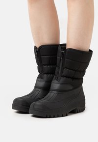 Sorte isolerte støvler med kviltet design, med glidelås, teksturert gummisåle og en slitesterk, vanntett finish.