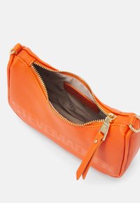 Orange synthetic handbag with a zippered opening, gold hardware, and embossed "STEVE MADDEN" on one side. Interior features a padded lining.