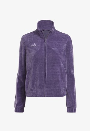 Giacca con zip in pile viola con collo alto, tessuto strutturato, tasche laterali e tre strisce diagonali sul petto.