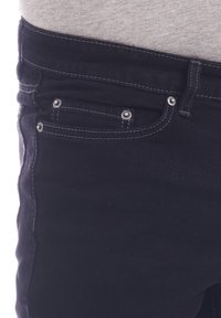 Jeans de mezclilla negra con costuras blancas contrastantes, diseño de cinco bolsillos y herrajes metálicos en la cintura y los bolsillos delanteros.
