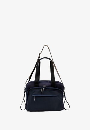 Borsa in tessuto blu navy con doppi manici superiori e tracolla regolabile. Presenta una tasca con zip sul davanti e un dettaglio del logo sulla parte anteriore.