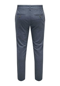 Pantalones de hombre a medida, de tejido azul oscuro, corte slim, dos bolsillos traseros con botones dorados, textura suave, patrón sutil.