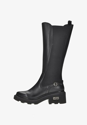 Bottes noires montantes en cuir et néoprène, avec un talon épais, un bout arrondi et une sangle décorative avec un accent argenté.