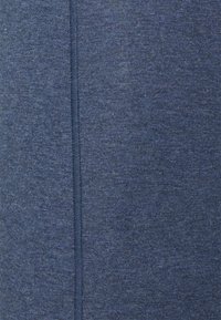 Zbliżenie na ciemnoniebieską dzianinę z pionowym szwem biegnącym wzdłuż środka.