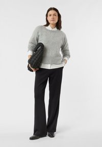 Szary wełniany sweter z okrągłym dekoltem, noszony na białej koszuli z kołnierzykiem. Czarne spodnie o szerokich nogawkach oraz pikowana czarna torba. Gładkie tekstury.