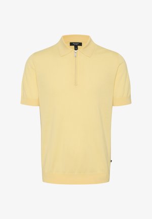 Īsām piedurknēm polo krekls gaiši dzeltenā krāsā, ar ceturtdaļas rāvējslēdzēju, gludu apkakli un ribotām piedurknēm. Mīksta, smalka adīta auduma.