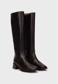 Bottes en cuir noir montant jusqu'au genou, avec un bout carré et un talon carré ; elles disposent d'une fermeture éclair sur le côté et d'une texture lisse.