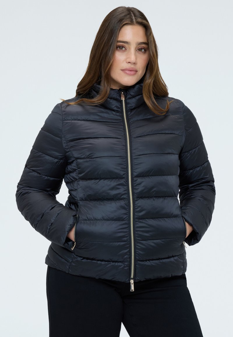 Chaqueta acolchada de marina con diseño acolchado, cuello alto, cremallera frontal y bolsillos laterales. Tejido liso y brillante con apariencia elegante.