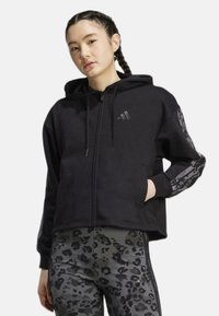 Felpa nera con zip in tessuto morbido, dotata di cappuccio e tasche. Presenta accenti in stampa animale nera sulle maniche e leggings abbinati.