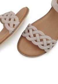 Light gray suede sandals featuring a braided strap design, a flat tan footbed, and a subtle textured sole.