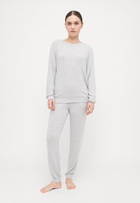 Ensemble de vêtements de détente gris clair en tissu doux, avec un col rond, des manches longues et un pantalon fuselé avec des poignets côtelés.