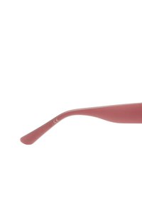 Różowe okulary przeciwsłoneczne o matowym wykończeniu. Smukłe, zakrzywione ramiona posiadają małe białe oznaczenie CE. Całościowy design jest smukły i minimalistyczny.