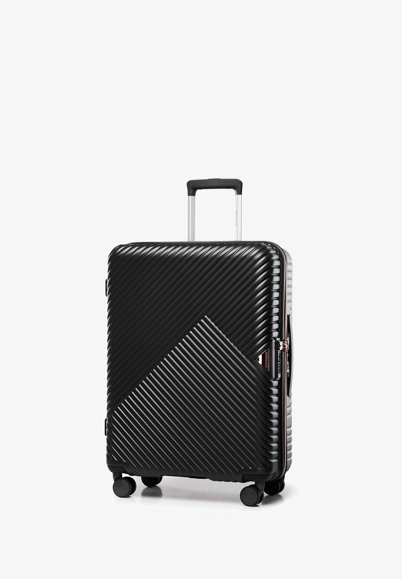 Valise rigide noire avec texture en relief diagonale, poignée télescopique, quatre roulettes et fermeture éclair avec un design géométrique.