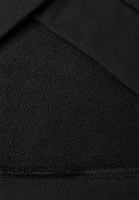Tessuto nero che mostra una superficie texture con un bordo liscio. Il materiale include trame dense e accenti a coste per un dettaglio aggiuntivo.