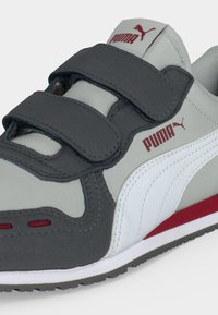 Γκρι, λευκό και κόκκινο αθλητικό παπούτσι Puma με δύο μαύρα λουράκια βέλκρο και λογότυπο Puma στο πλάι και στη γλώσσα.