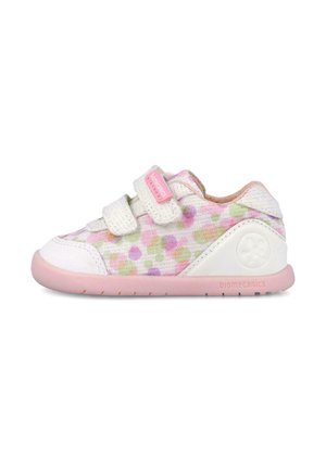 Zapatilla para niño pequeño de color blanco y rosa con lunares pastel, dos tiras de velcro blancas y una suela flexible de color rosa claro.