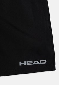 Calções atléticos pretos com uma textura suave, com bainha cosida e um logo refletor prateado "HEAD" no canto inferior esquerdo.