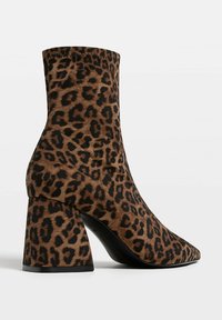 Ankle-high block heel boot with brown and black leopard print pattern, pointed toe, and side seam detailing.