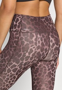 Κολάν με μοτίβο λεοπάρ σε αποχρώσεις καφέ και ροζ, με ψηλή μέση και λογότυπο "DRYCELL", κατασκευασμένο από λείο, ελαστικό υλικό.