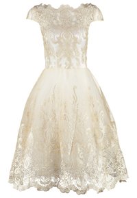 Robe en dentelle à épaules dénudées avec un corsage cintré et une jupe évasée longueur genou. Présente une broderie dorée et un ourlet festonné. Couleur ivoire.