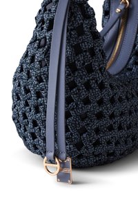 Woven fabric handbag in dark blue with leather accents. Features a zip closure, flat straps, and a gold-tone hardware tag. Textured surface.