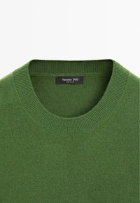 Pull vert à col rond avec col côtelé, montrant une étiquette noire avec le texte « Massimo Dutti » et « Made in China ».