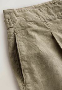 Helle olivgrüne Shorts aus einem strukturierten Stoff mit dezenten Blattmustern, flachem Bund und seitlichen Taschen.