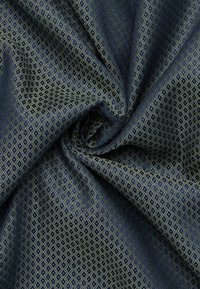 Blauwe stof met een herhalend ruitpatroon in zwart en beige, samengevoegd in een zachte spiraalvorm die textuur en detail toont.