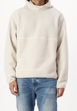 Krämfärgad huvtröja i texturerad fleece med hög hals, långa ärmar och rak nederkant. Kombineras med ljusblå jeans.